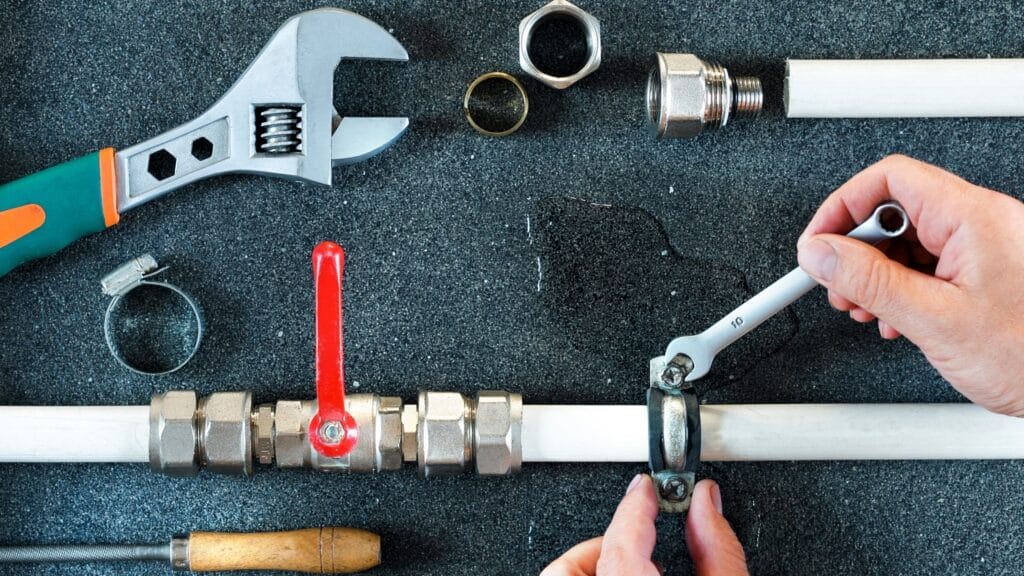 Plumber repairing a pipe valve with an adjustable wrench in Immokalee