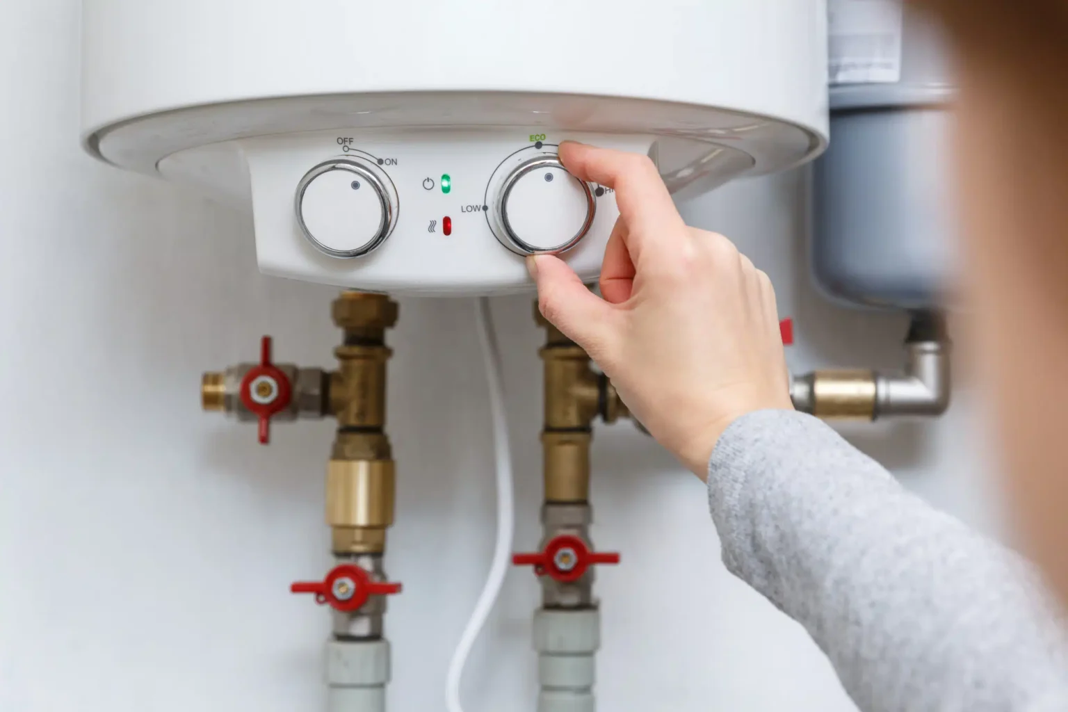 Homeowner adjusting the temperature controls on a water heater in Immokalee
